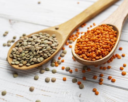 Different raw lentils on a white wooden background